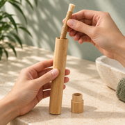 Hand sliding a miswak stick into the slim bamboo travel case